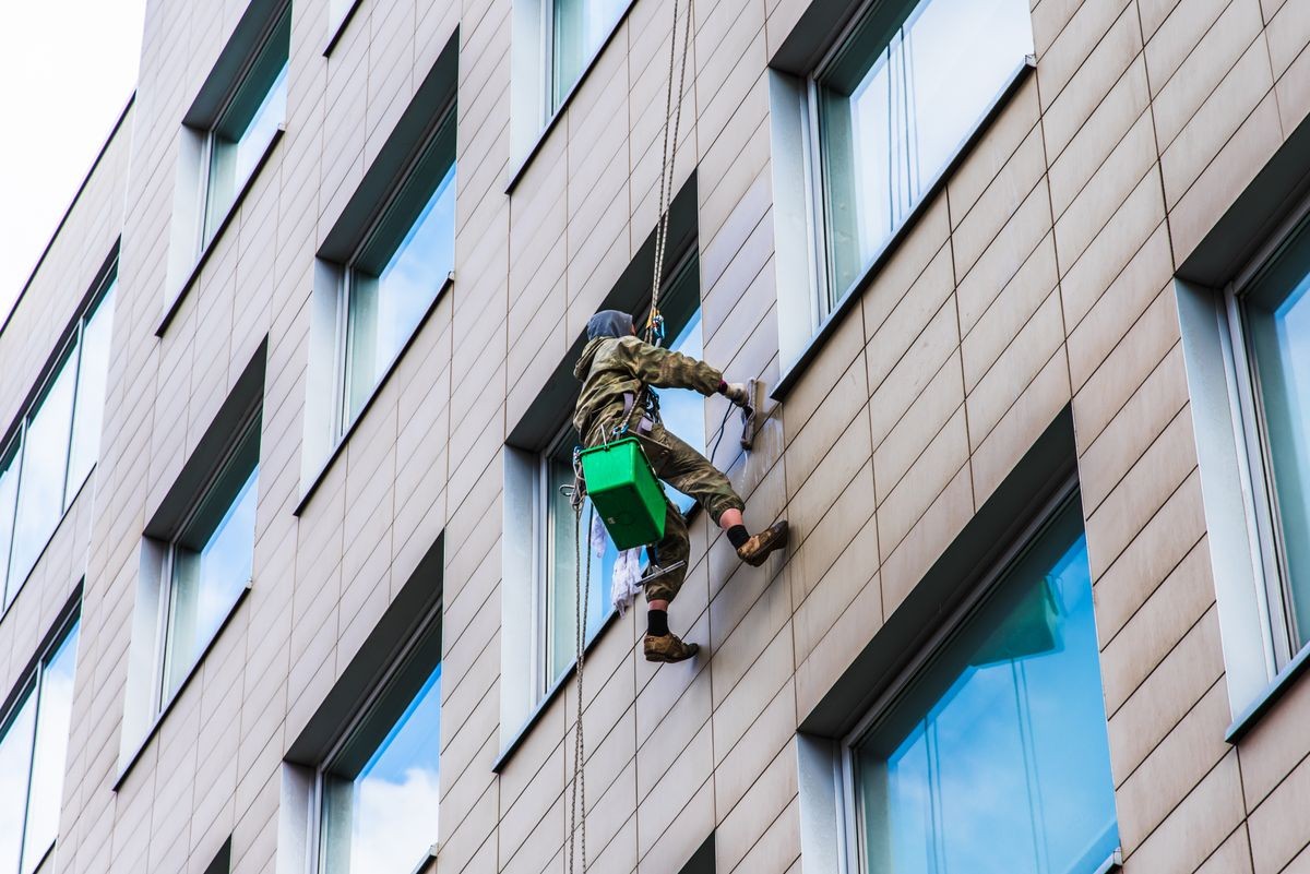 Working climber washes facade of a commercial building